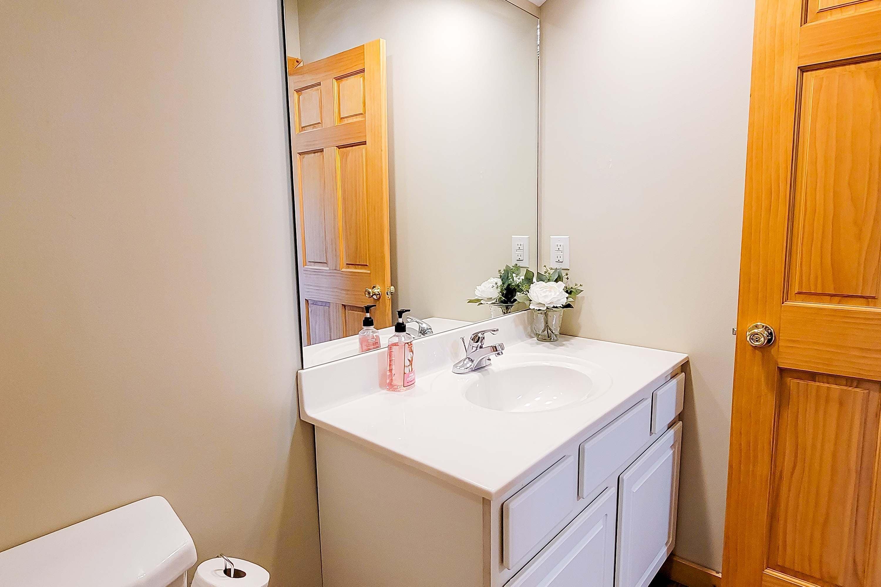 A bathroom with a white sink, mirror, and wooden door.