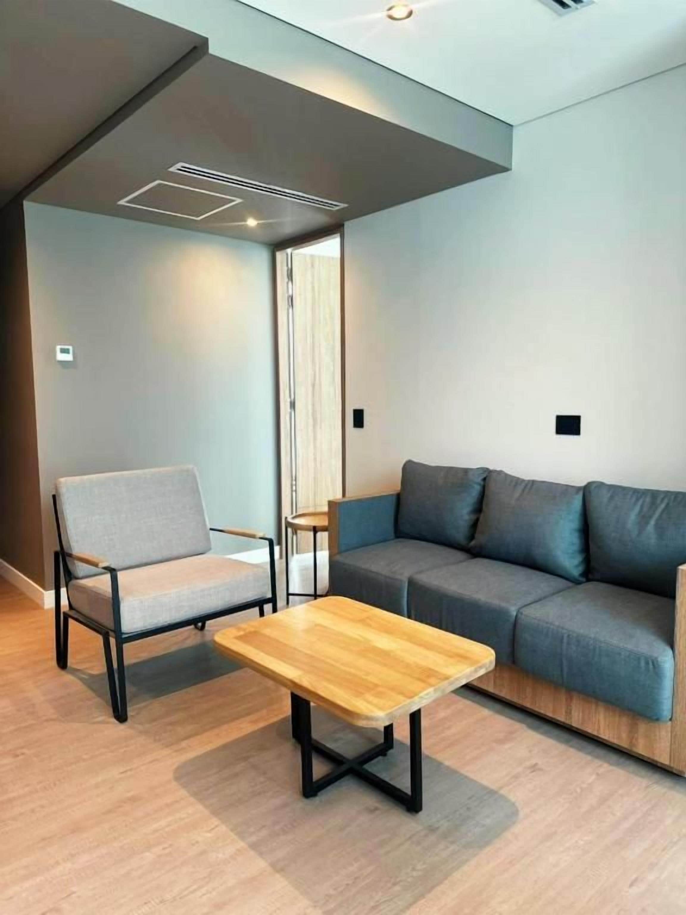 Uma sala de estar moderna com um sofá, uma poltrona e uma mesa de centro de madeira.