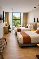Habitación de hotel con dos camas, un escritorio, una silla y vistas al exterior.