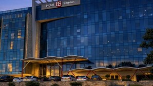 A modern hotel building with a glass facade, a prominent entrance with a covered walkway, and a well-maintained lawn. - Hotel B3 Sibelius (Chía)