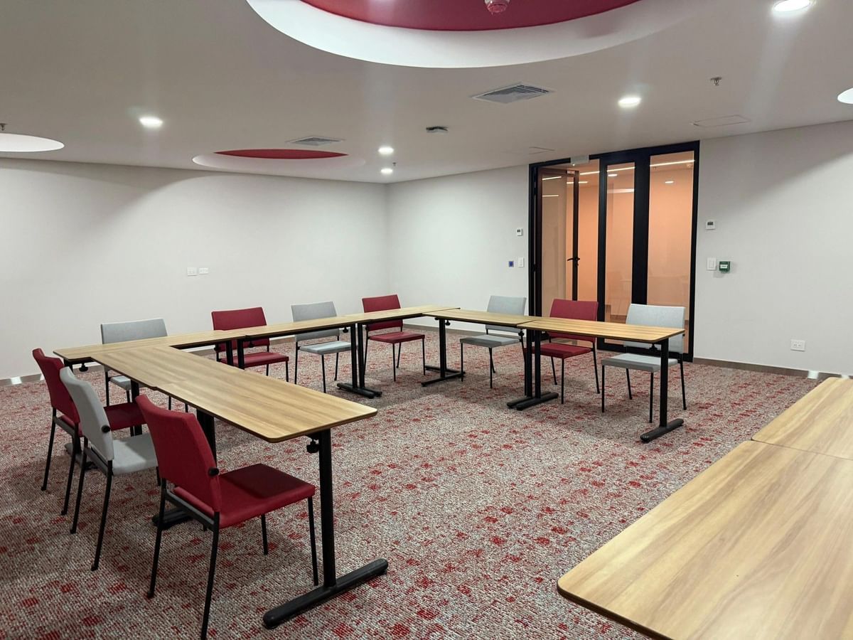 A conference room with a long table and chairs, carpeted floor, and recessed lighting.