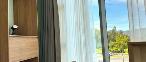 A room with a large window, a wooden bench, and a built-in shelf unit.