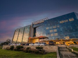 Un hotel moderno con fachada de vidrio, entrada cubierta y zona de estacionamiento.