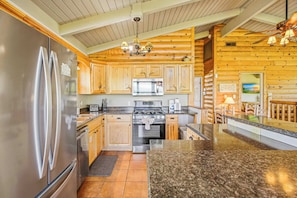 A kitchen with wooden cabinets, stainless steel appliances, granite countertops, and a chandelier. - Chalet Village Cabin, Sleeps 9, Mtn View, 360 Deck (Gatlinburg)