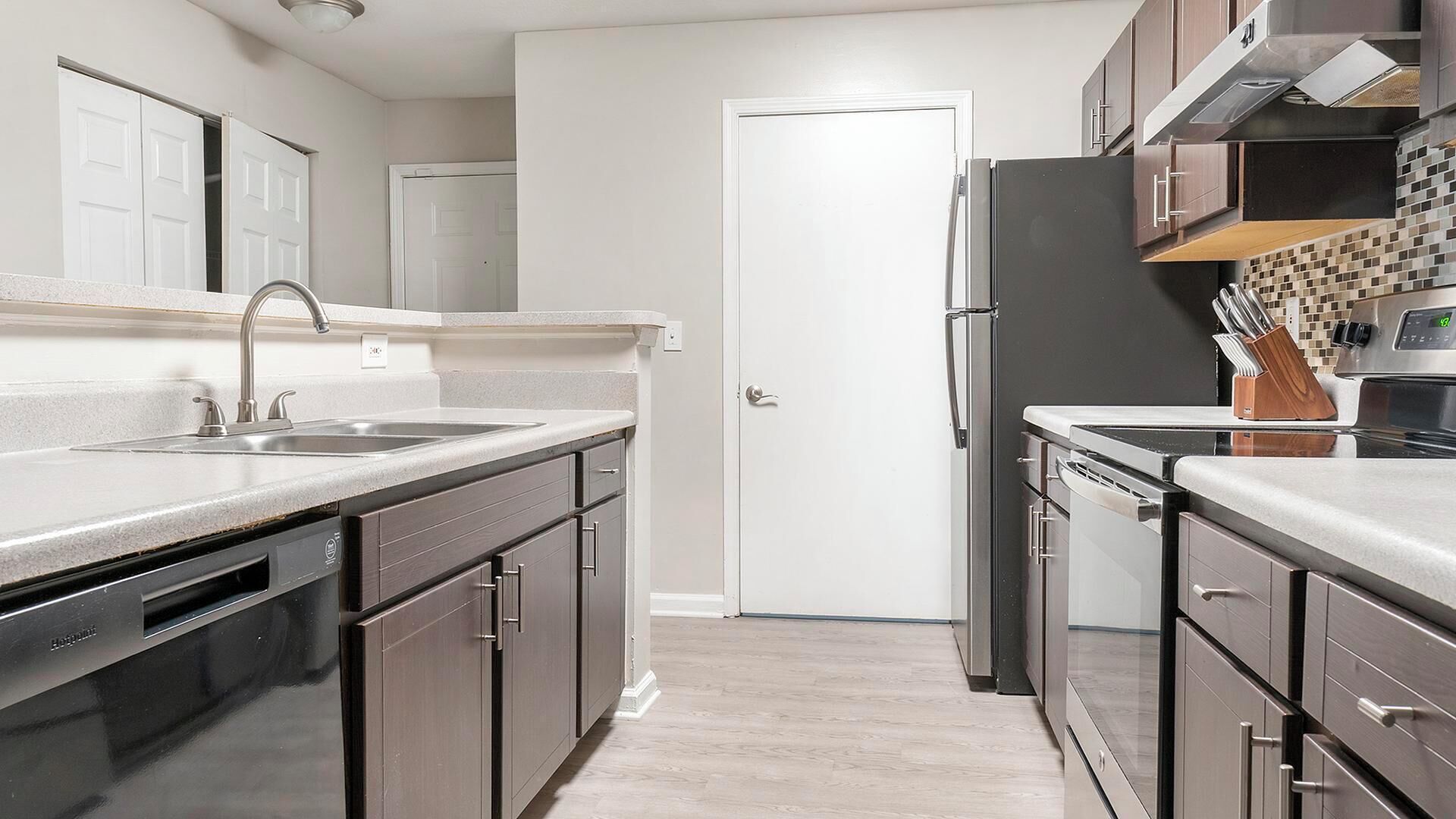 A modern kitchen with stainless steel appliances, a double sink, and dark cabinetry.