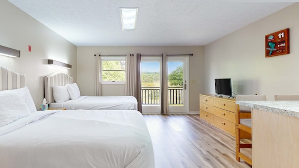 A hotel room with two beds, a wooden dresser, a TV, and a balcony with a view. - Peaceful Studio, Sleeps 4, Gym, Near Douglas Lake (Baneberry)