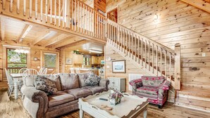 L’intérieur d’une cabane en bois comprend un salon, un coin repas et un escalier.