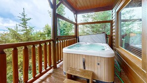 Une terrasse en bois avec un jacuzzi, des rampes en bois et une vue sur les arbres.