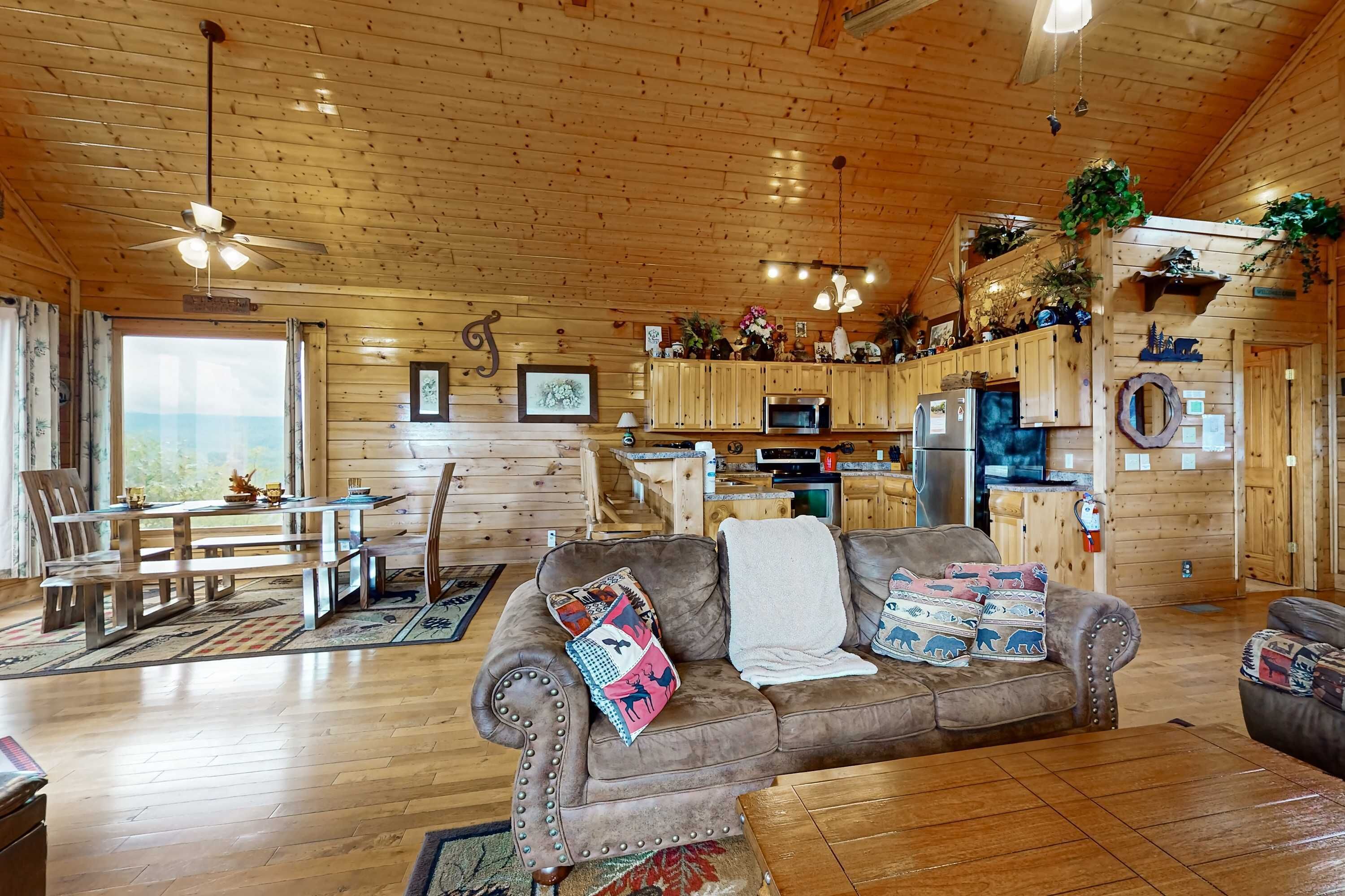 A cozy cabin interior with a dining area, a sofa, and a kitchen.