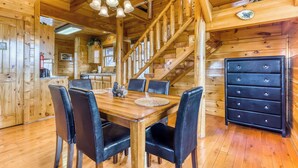 A wooden cabin interior with a dining table, chairs, a staircase, and a dresser. - Charming Log cabin, Sleeps 6・Game Room・Hot Tub (Pigeon Forge)