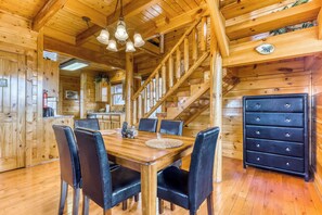 A wooden cabin interior with a dining table, chairs, a staircase, and a dresser. - Charming Log cabin, Sleeps 6・Game Room・Hot Tub (Pigeon Forge)