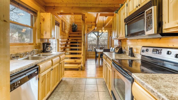 A wooden cabin kitchen with granite countertops, a built-in microwave, and a stove. - Charming Log cabin, Sleeps 6・Game Room・Hot Tub (Pigeon Forge)