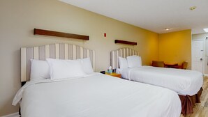 Una habitación de hotel con dos camas, una mesita y una silla.