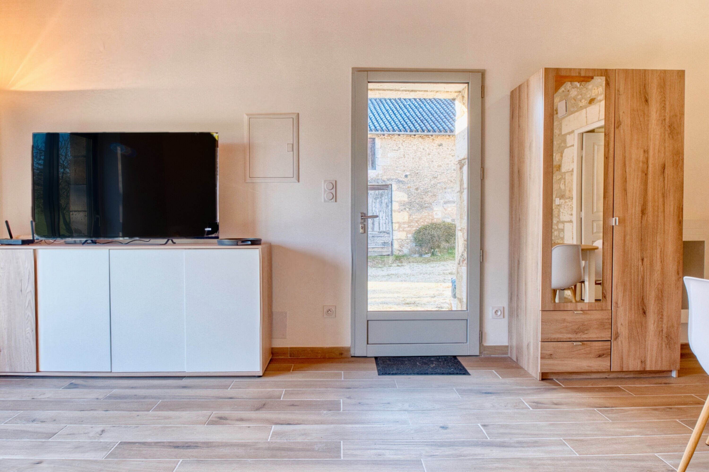 Una cocina moderna con televisión integrada, una puerta corrediza que da a un espacio exterior y un armario de madera con cajones.