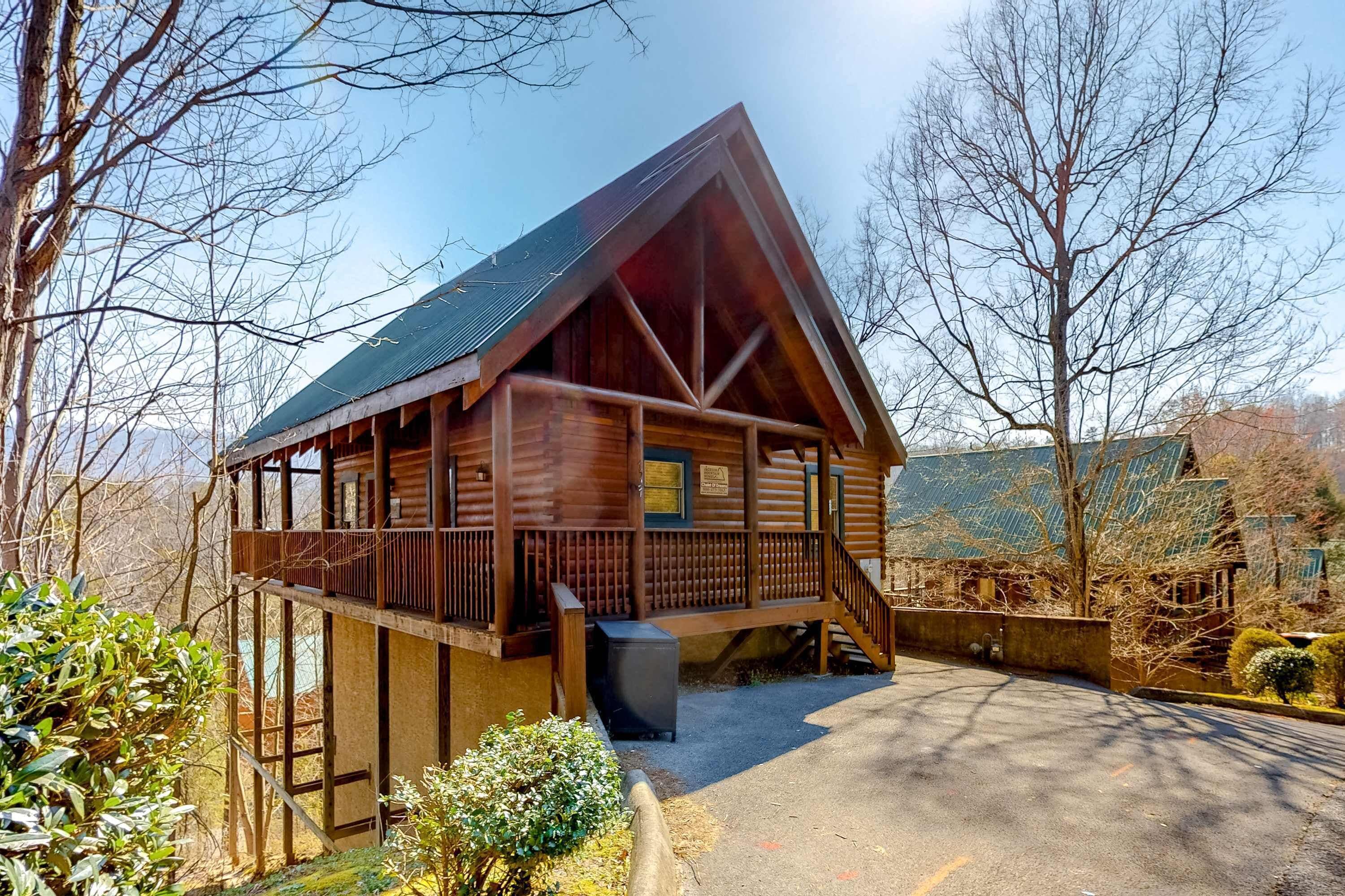 A wooden cabin with a balcony, a covered porch, and a small attached shed.