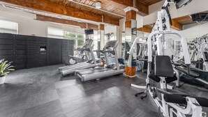 A gym with treadmills, weight machines, and a mirrored wall. - Landing | Incredible 1BD, Courtyard, Gym (Baltimore)