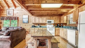 L’intérieur d’un chalet en bois comprend une cuisine, un coin repas et un canapé.