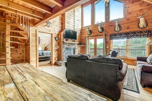 Ein Blockhaus-Interieur mit Kamin, Ledersofas, einem Steinkamin und aufgehängten Hirschköpfen.