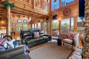 L’intérieur d’une cabane en rondins, avec un canapé en cuir, des fauteuils et un coin repas.