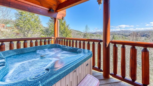 A hot tub on a wooden deck with a wooden railing, overlooking a mountainous landscape. - Family Friendly Luxe Mtn Getaway・Near Downtown (Pigeon Forge)