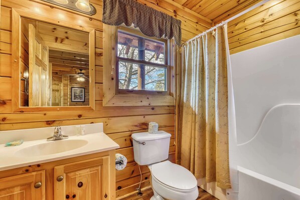 A wooden cabin bathroom with a sink, toilet, and bathtub.