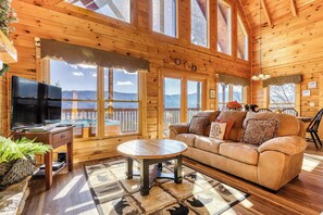 A cozy wooden cabin interior with a sofa, TV, and a dining area.