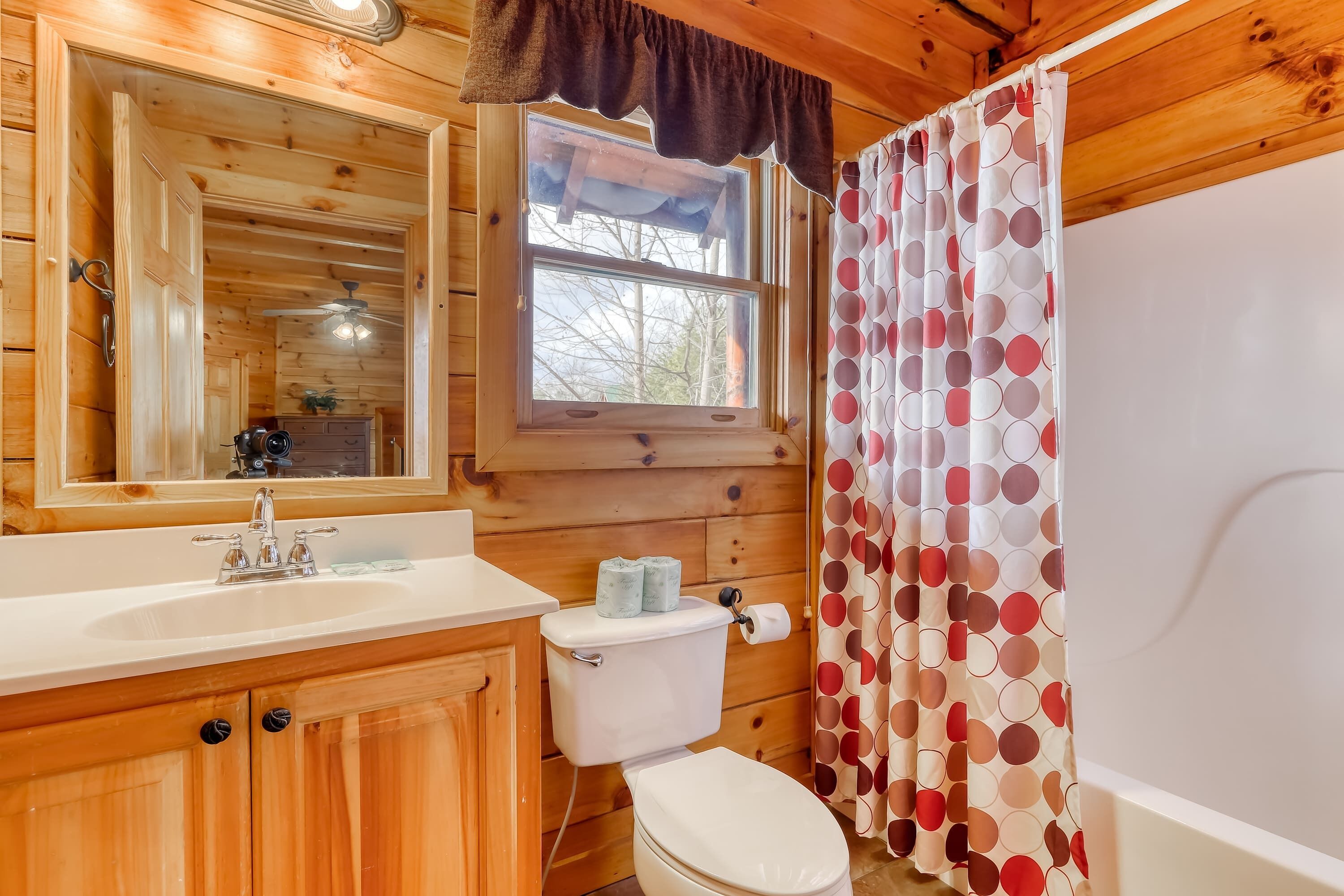 A wooden cabin bathroom with a wooden sink, toilet, and a window above the sink.
