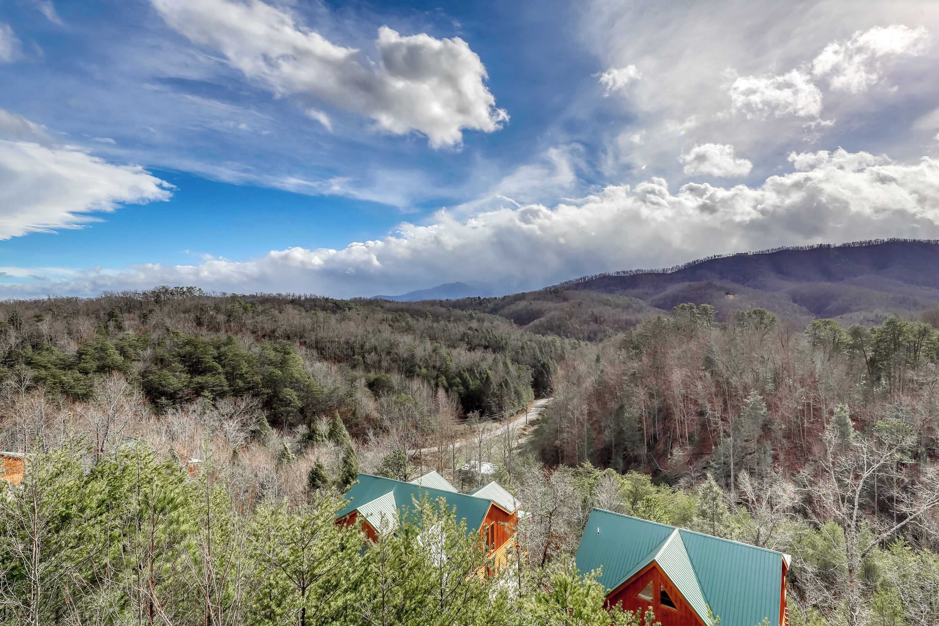 A cabin with a green roof nestled in a forested area with a clear sky.