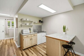 A kitchen with wooden cabinets, a microwave, a sink, and a small island with stools.