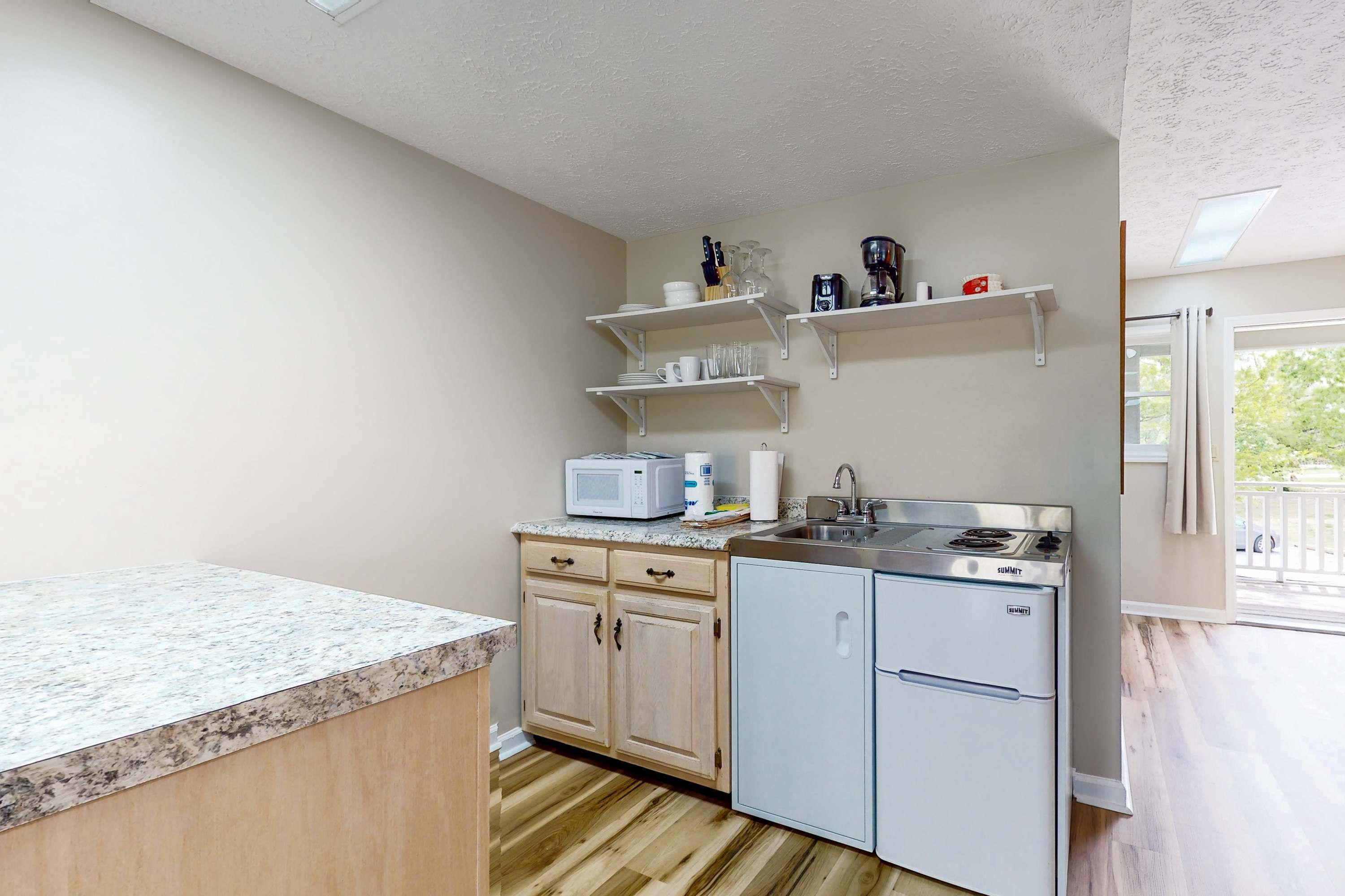 A compact kitchen with a microwave, refrigerator, and wooden cabinets.