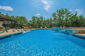 Une piscine d’un bleu éclatant, dotée de chaises longues et agrémentée d’une petite cascade.