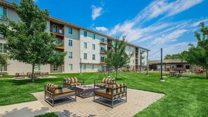 A multi-story apartment building with a courtyard featuring outdoor seating and a fire pit. - Landing | Stunning 1BD, Courtyard (Springfield)
