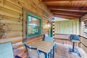 Eine Holzhütte mit Veranda, einem Tisch mit Stühlen und einem Grill.