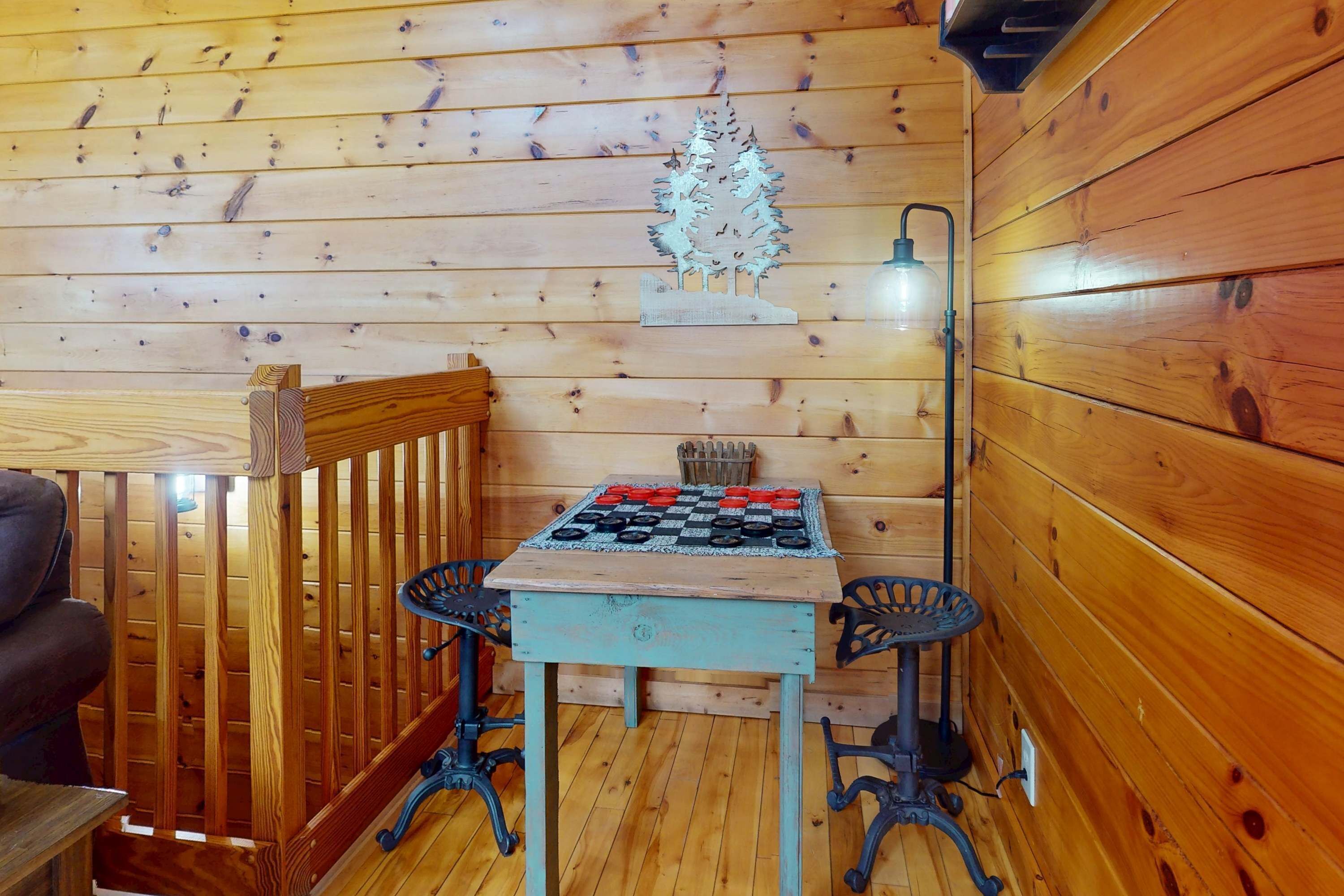 Ein Holzinterieur mit einem Schachbrett, zwei Stühlen, einer Lampe und einem Zierbaum.