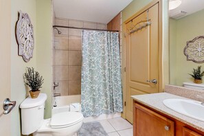Ein Badezimmer mit Toilette, Waschbecken, Dusche und einer Tür mit Handtuchhalter.