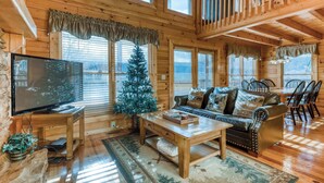 Ein gemütliches Blockhaus-Interieur mit Fernseher, Weihnachtstanne, Sofa und Essbereich.