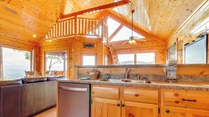 Una cabaña de madera con cocina equipada con lavavajillas, encimera de granito y armarios de madera.