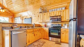Cocina de cabaña de madera con lavavajillas integrado, electrodomésticos de acero inoxidable y un letrero que dice "KITCHEN".