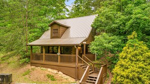 A cabin with a wooden exterior, a porch, and a staircase leading to the entrance. - Cabin near Dolly - Parkway・Hot Tub・Screened Porch (Pigeon Forge)