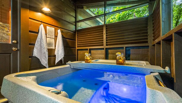 A spa area with two hot tubs, wooden walls, and a window with greenery outside. - Cabin near Dolly - Parkway・Hot Tub・Screened Porch (Pigeon Forge)
