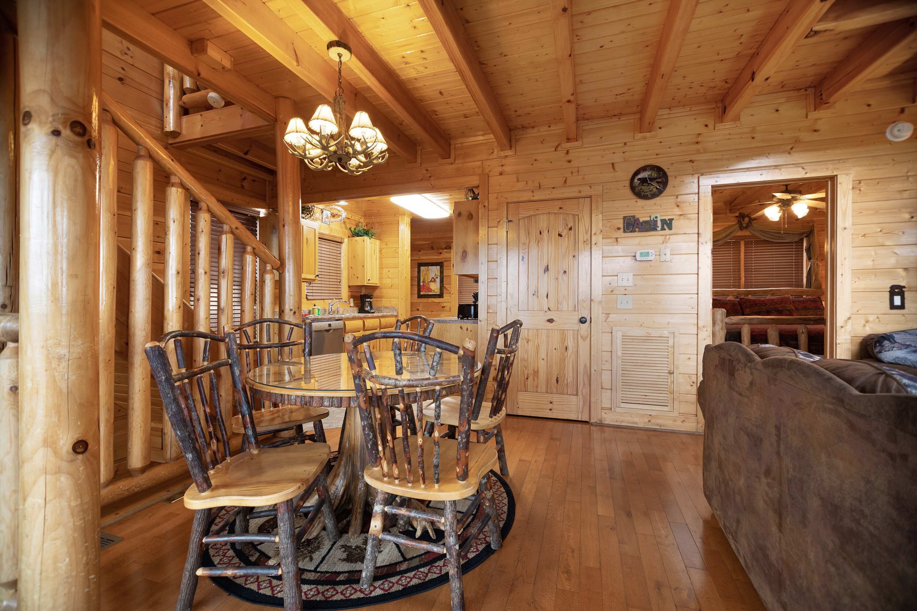 A wooden interior with a dining area, a sofa, and a ceiling fan.