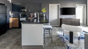 A modern kitchen with dark cabinetry, a central island, and a built-in oven. - Landing | Incredible 3BD, Courtyard (Springfield)
