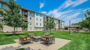 A multi-story apartment building with a courtyard featuring outdoor seating and a fire pit. - Landing | Incredible 3BD, Courtyard (Springfield)