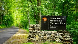 Een stenen muur met een bord voor Great Smoky Mountains National Park in Deep Creek.