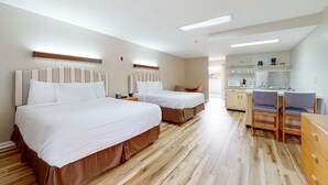 Hotellihuone, jossa on kaksi sänkyä, pieni keittiö ja oleskelualue.