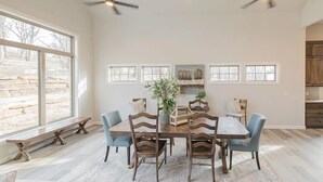 A dining room with a wooden table and chairs, two ceiling fans, and large windows. - Landing | Incredible 3BD, Pool, Gym (Sapulpa)