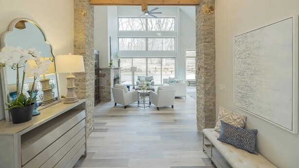 A spacious living area with a stone accent wall, a fireplace, and a view of the outdoors. - Landing | Incredible 3BD, Pool, Gym (Sapulpa)