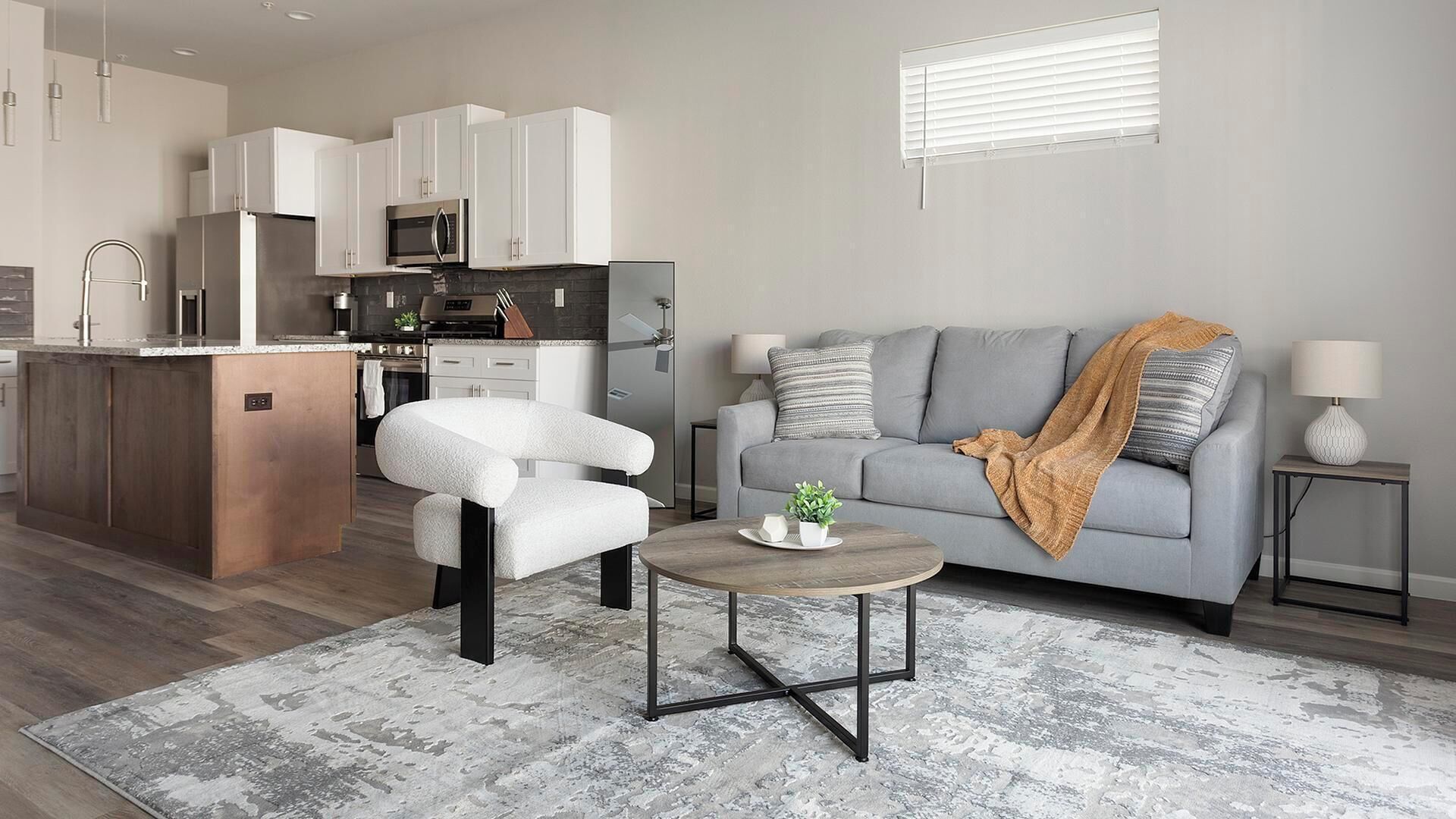 A modern living room with a grey sofa, a white armchair, and a coffee table.