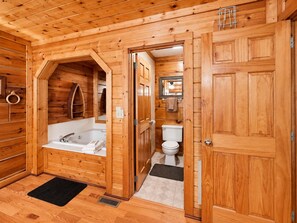 A wooden cabin bathroom with a bathtub, toilet, and a shower area. - Cozy Creekside Cabin Near Pigeon Forge | Sleeps 4 (Pigeon Forge)