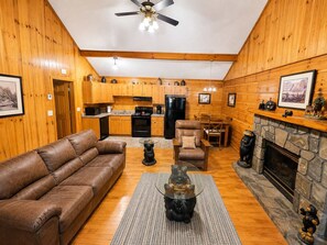A cozy cabin interior with a living room, kitchen, and fireplace. - Cozy Creekside Cabin Near Pigeon Forge | Sleeps 4 (Pigeon Forge)